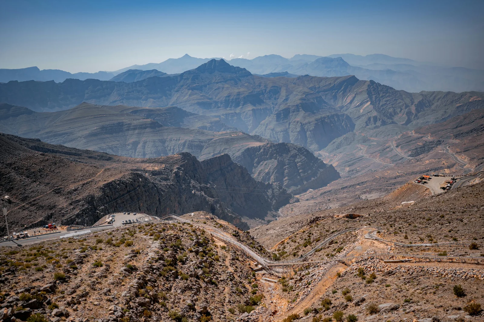 Layered rocky ridges and a winding road seen from Jebel Jais